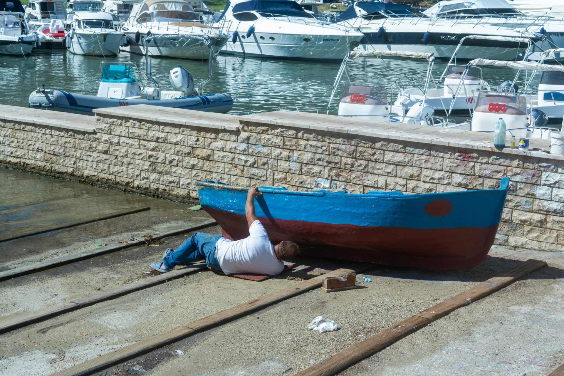 A man repairing his boat at Marinella di Selinunte marina in Sicily, Italy.